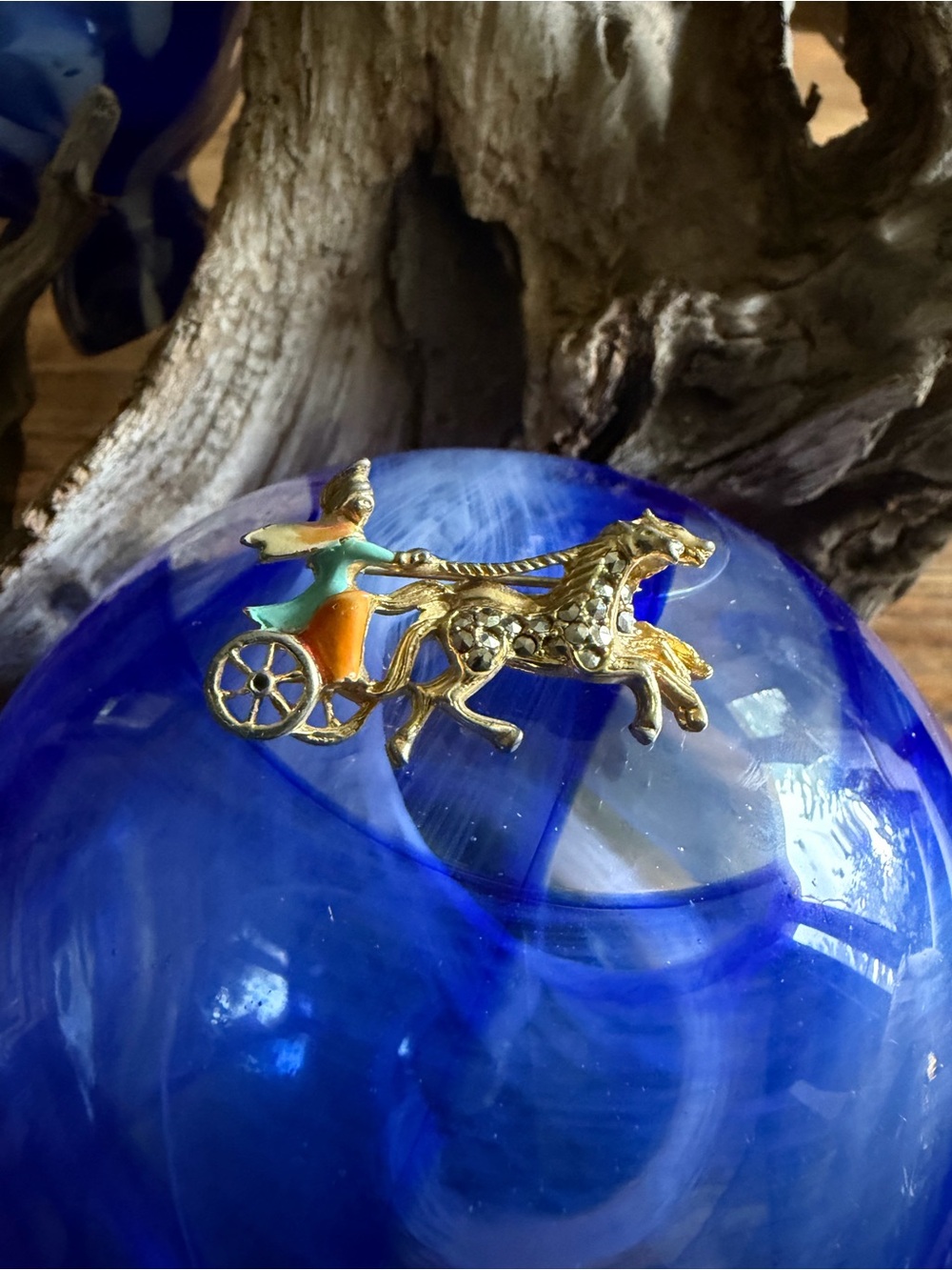 Vintage brooch, featuring an enameled driver of a gold toned chariot.